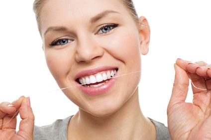 Una donna sorridente passa il filo interdentale