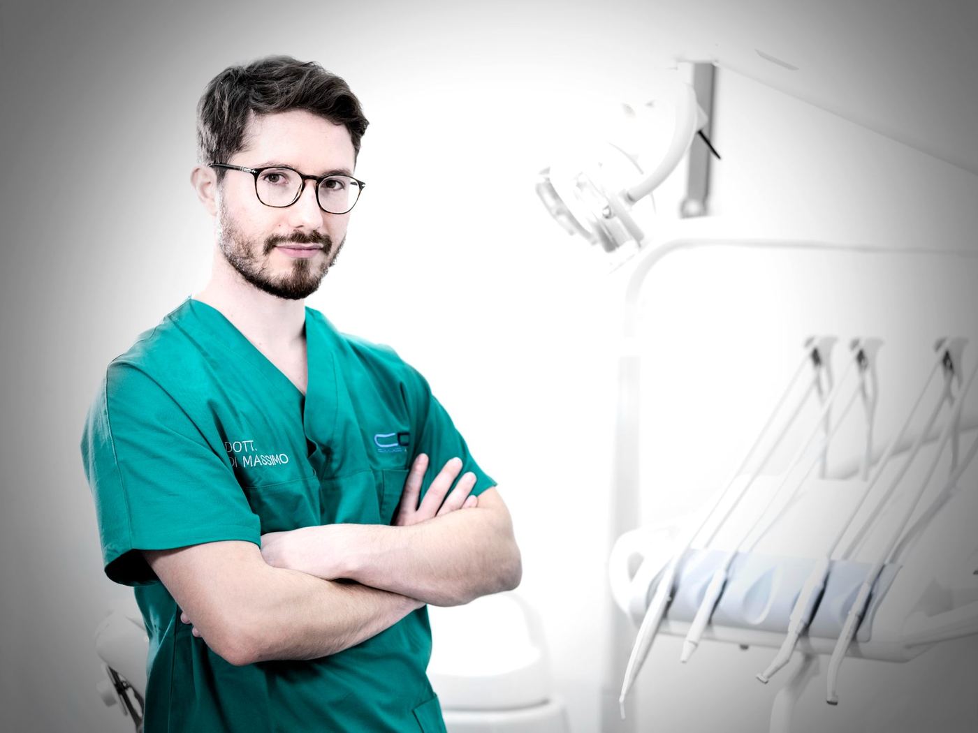 Un odontoiatra in divisa verde, a braccia conserte